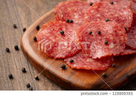 Delicious slices of salami on a wooden cutting board 128808383