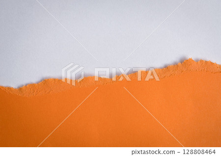 Torn orange paper on top of white color paper. 128808464