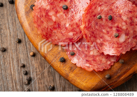 Delicious slices of salami on a wooden cutting board 128808489