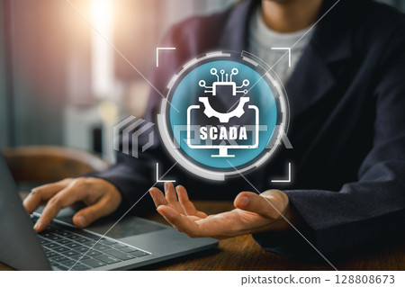 Engineer interacts with SCADA system on laptop, showcasing industrial automation and control technology. 128808673