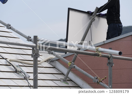 Installation of solar panels on the roof of a house 128809179