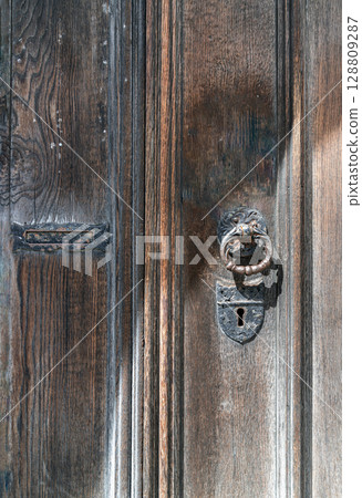 Aged wooden door with Ornamental keyhole and knocker, Antique wooden gate of Holy trinity church. Aged wooden door with Ornamental keyhole and knocker, Antique wooden gate of Holy trinity church. 128809287