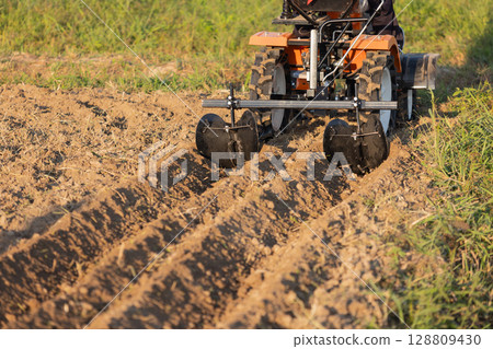Mini Tractor with attachments to make the furrows in garden. Mini Tractor with attachments to make the furrows in garden. 128809430