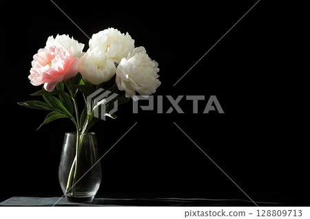 Peonies in a glass vase against a dark background 128809713