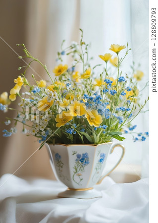 Bright spring flowers in a vintage teacup on a soft fabric surface 128809793