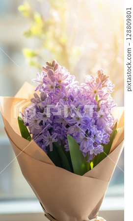 Purple hyacinth flowers in a brown paper bouquet with sunlight in the background 128809801