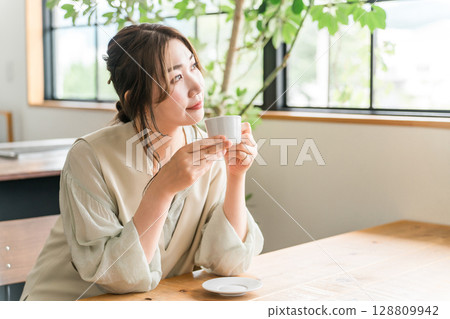 年輕的亞洲女性在咖啡館、餐廳喝咖啡 年輕的亞洲女性在咖啡館、餐廳喝咖啡 128809942