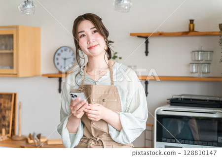 在家庭廚房/餐廳使用智能手機應用程序的亞洲女性 128810147