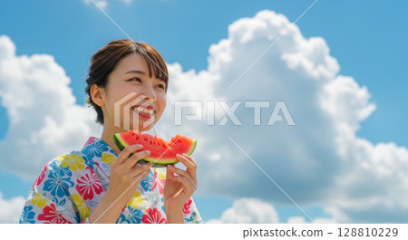 一位身著浴衣的女子在藍色夏日天空下吃西瓜 128810229
