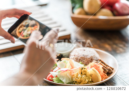 一位女士用智慧型手機拍攝食物的照片 128810672
