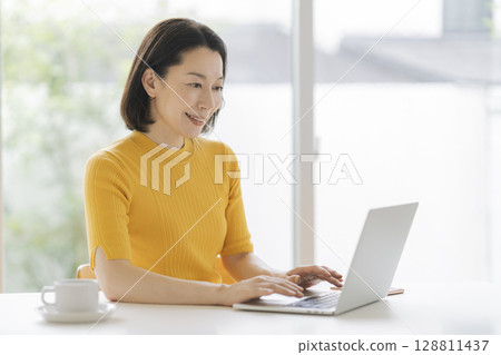 一位 50 多歲的女性正面對著筆記型電腦 一位 50 多歲的女性正面對著筆記型電腦 128811437