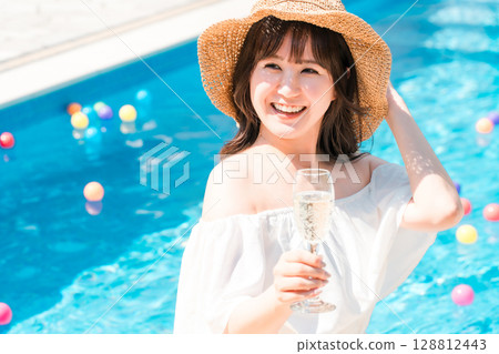 戴草帽的年輕女子在泳池邊喝礦泉水 128812443