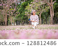 Elderly women with gray hair enjoying a beautiful moment together outdoors, surrounded by blooming pink flowers expressions reflect deep friendship and happiness relaxation with nature. 128812486
