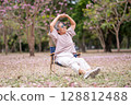 Elderly women with gray hair enjoying a beautiful moment together outdoors, surrounded by blooming pink flowers expressions reflect deep friendship and happiness relaxation with nature. 128812488