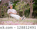 Elderly women with gray hair enjoying a beautiful moment together outdoors, surrounded by blooming pink flowers expressions reflect deep friendship and happiness relaxation with nature. 128812491