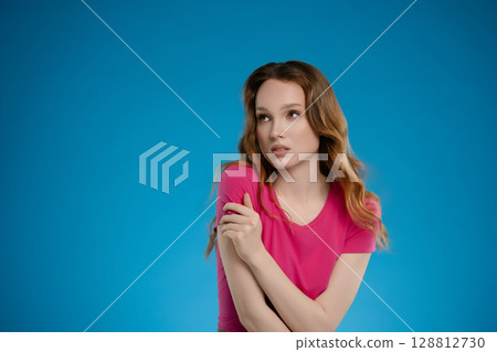 Woman poses in a studio setting with emotional expression against a solid blue background 128812730