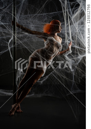 Red-haired woman entrapped in web-like net in dramatic lighting 128812766