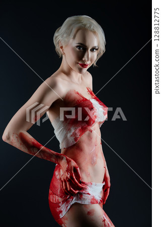 Naked woman poses dramatically with blood body art in a studio setting 128812775