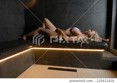Relaxation moment for a woman in a sauna during a tranquil spa experience 128812820