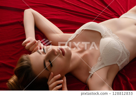 Woman poses gracefully in a beauty studio with red backdrop and soft lighting Woman poses gracefully in a beauty studio with red backdrop and soft lighting 128812833