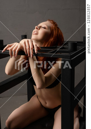 Beautiful woman poses in lingerie with BDSM furniture in an artistic setup Beautiful woman poses in lingerie with BDSM furniture in an artistic setup 128812857