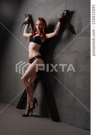 Beauty woman confidently posing with BDSM furniture in a modern setting 128812895