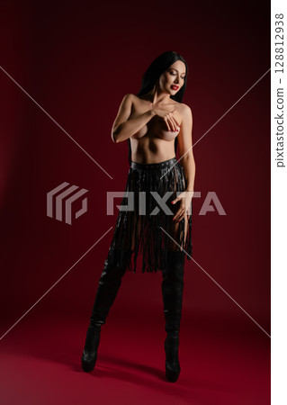 Elegant woman posing with leather accessories in a studio setting Elegant woman posing with leather accessories in a studio setting 128812938