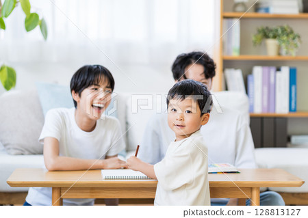 A child drawing while his parents watch. A child drawing while his parents watch. 128813127