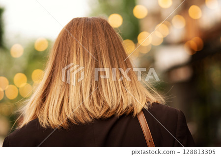 Back view of blonde woman with shoulder-length hair outdoors. Back view of blonde woman with shoulder-length hair outdoors. 128813305