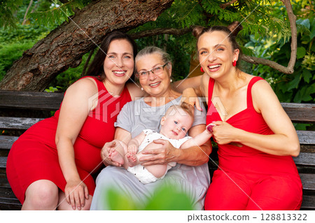 Happy three-generation family posing on park bench outdoors Happy three-generation family posing on park bench outdoors 128813322