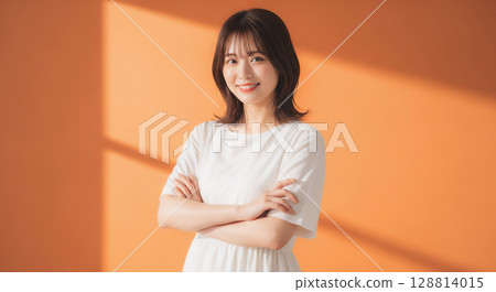 橙色背景中自然微笑的年輕女子肖像 128814015