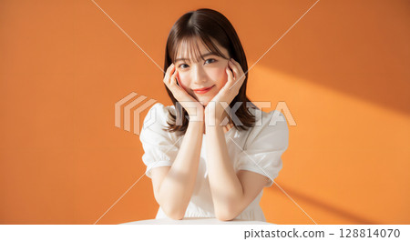 Natural smiling young woman portrait on orange background Natural smiling young woman portrait on orange background 128814070