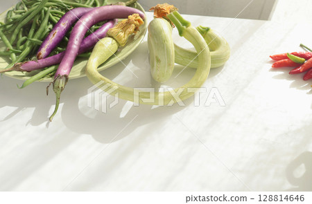 Unusually shaped vegetables on white background. Zucchini and eggplant, asparagus beans and peppers. Seasonal food and farm organic produce. 128814646
