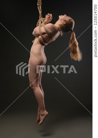 Woman suspended with shibari rope in a sensual bondage display 128814700
