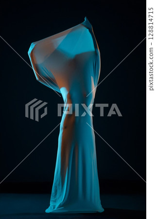Elegance in motion as a woman dances gracefully with flowing fabric 128814715