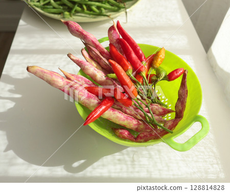 Bunch of red peppers and pink beans in green colander. Seasonal food and farm organic produce. Bunch of red peppers and pink beans in green colander. Seasonal food and farm organic produce. 128814828