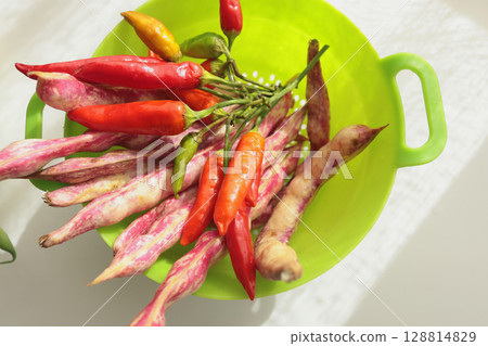 Bunch of red peppers and pink beans in green colander. Seasonal food and farm organic produce.  128814829