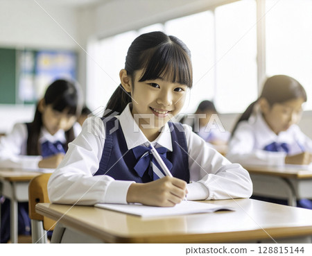 微笑的日本小學生在筆記本上學習：在明亮的教室裡學習 128815144