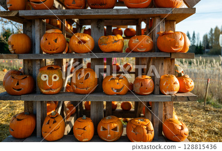 Funny carved Halloween pumpkins on wooden shelf at autumn festival 128815436