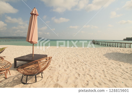 A solitary umbrella and wicker chairs facing the vast sea on a sunny summer day on the island of Koh Rong Sanloem, Sihanoukville, Cambodia 128815601