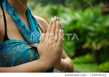 A woman does yoga outdoors amid greenery A woman does yoga outdoors amid greenery 128816202