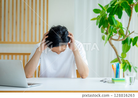 一名男子在使用筆記型電腦時抱著頭 128816263