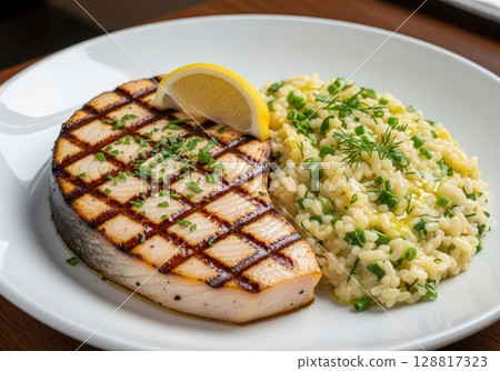 Grilled swordfish steak with creamy herb risotto and a lemon wedge on a white dinner plate Grilled swordfish steak with creamy herb risotto and a lemon wedge on a white dinner plate 128817323