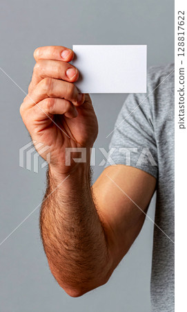 Close up of a hand holding a blank white card against a gray background 128817622