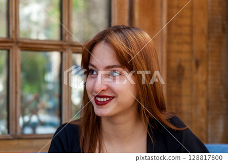 Smiling woman with red hair in cozy cafe setting 128817800