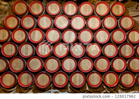 Stacked wooden wine barrels with red rims 128817962