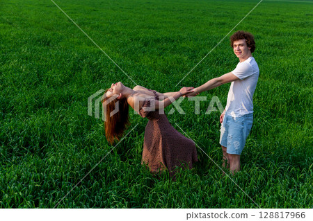Young couple having fun in green field at sunset 128817966