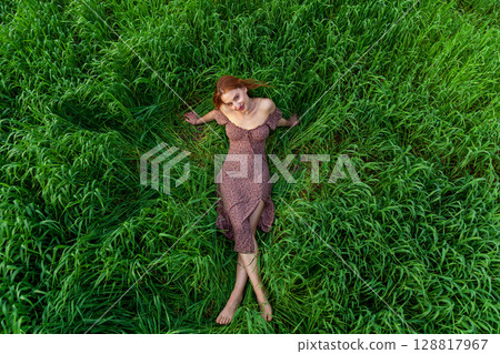 Woman lying in tall green grass in summer meadow Woman lying in tall green grass in summer meadow 128817967