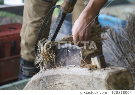 A man cutting straw with a straw cutter 128818004