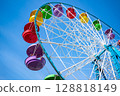 Ferris wheel with colorful cabins against a clear sky 128818149